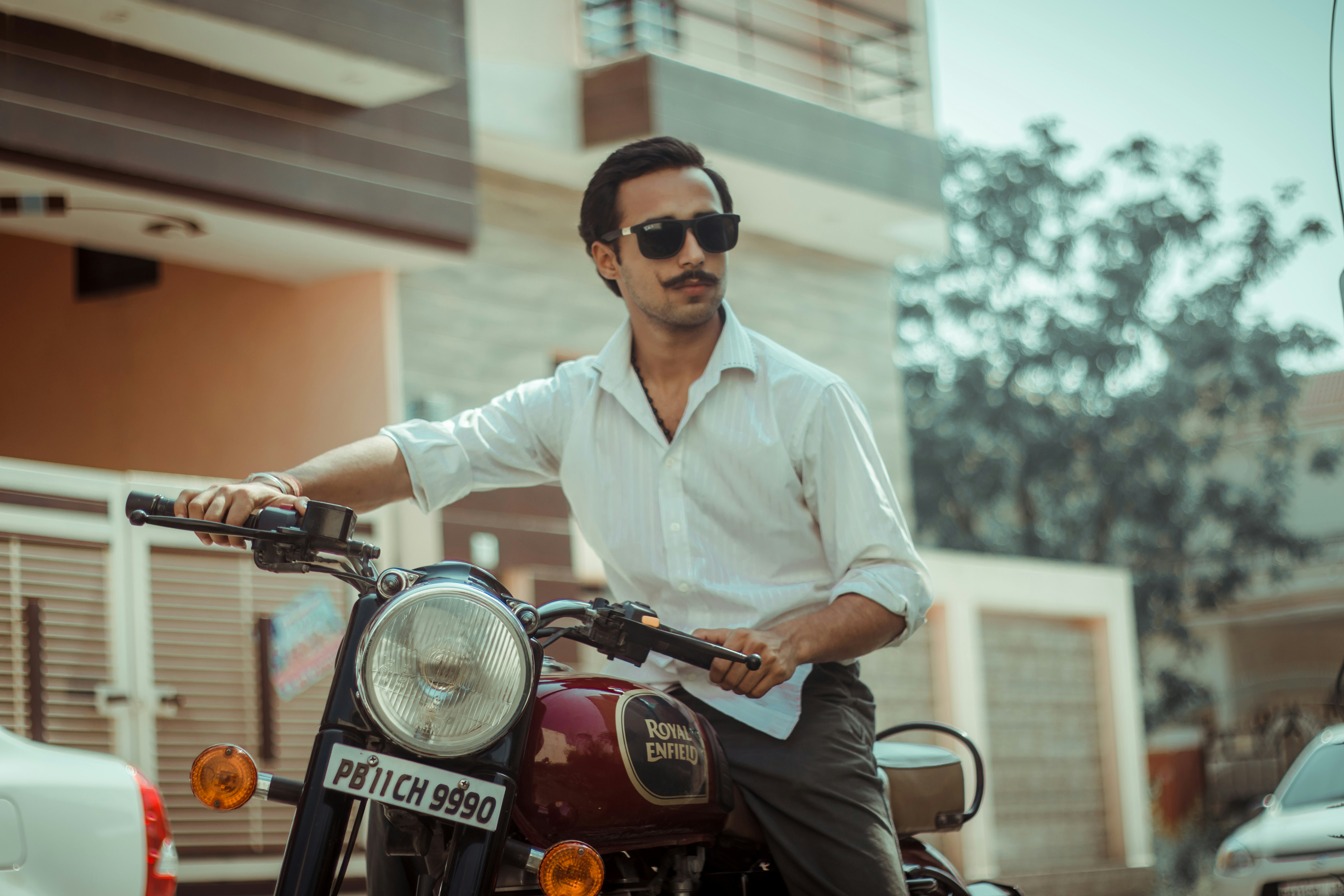 man in white dress shirt wearing black sunglasses riding red motorcycle during daytime